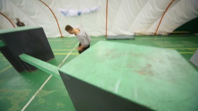 Agile guy overcomes obstacles on place for parkour training