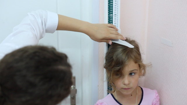 woman doctor measures growth of little girl by ruler