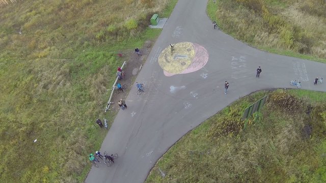 People with bicycles stand at t-shaped crossroad 