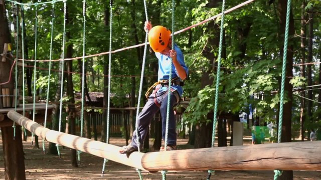boy takes rope and steps to next pendant tree log