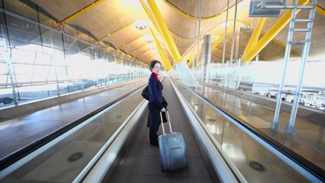 Woman rides with luggage by empty hallway in Barajas Airport