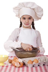 Little cook girl in a white apron breaks eggs in a deep dish