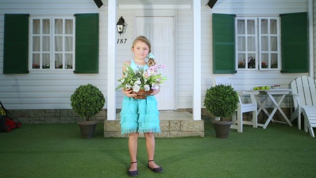 Little girl stands in front of house holding flower pot