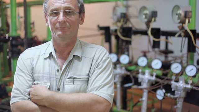 Old man stands in boiler room with several manometers on tubes