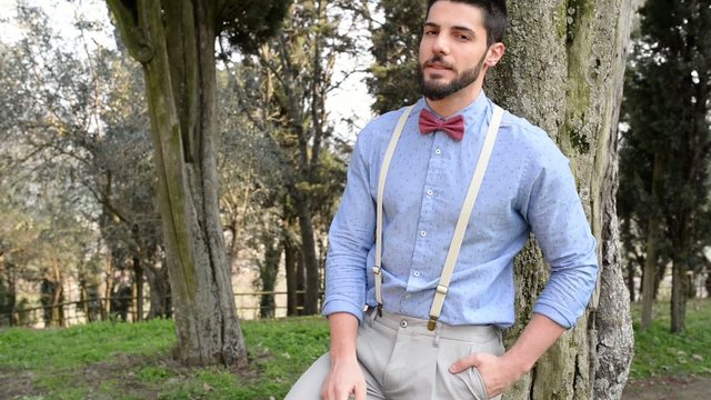 Hipster young man relaxing smoking a cigarette outdoors in a par