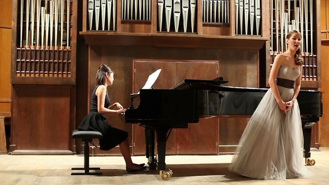 woman pianist and opera singer start the performance at stage