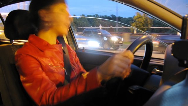 Beautiful woman goes in car in evening fastened by seat belt