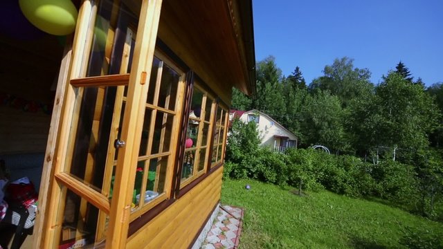 Little girl walk at terrace of wooden house at summer day