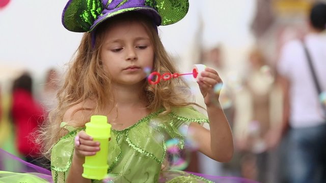Little girl inflates soap bubbles on holiday of spring