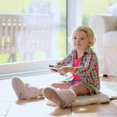 Cute preschooler girl watching tv at home