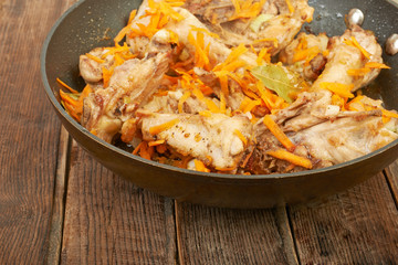 Fried chicken in the pan on a wooden background