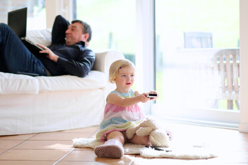 Father and little daughter watching tv at home