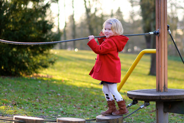 Little girl in red coat playing at the park in spring