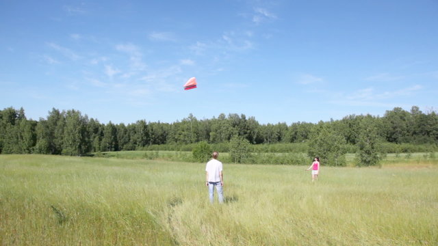 girl holds rope from kite, and guy nearby looks in field