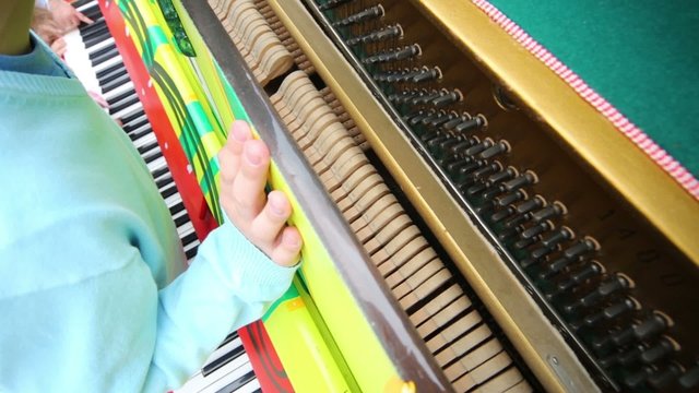 Children hands playing at piano during the day. girl