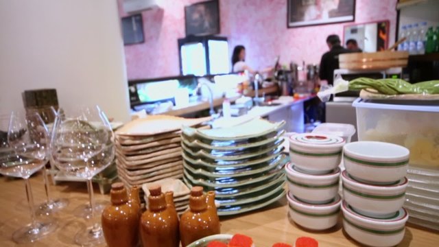 Rolls on plate and glassware at counter of bar with people
