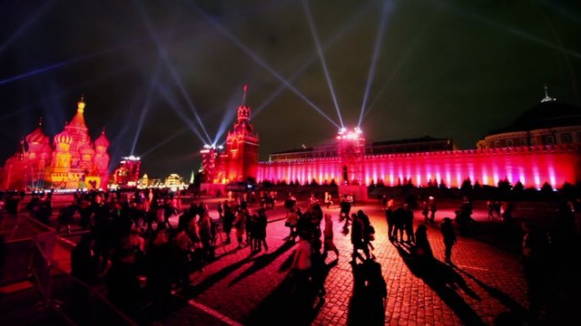 Projectors rays in dark sky above crowd on Red Square