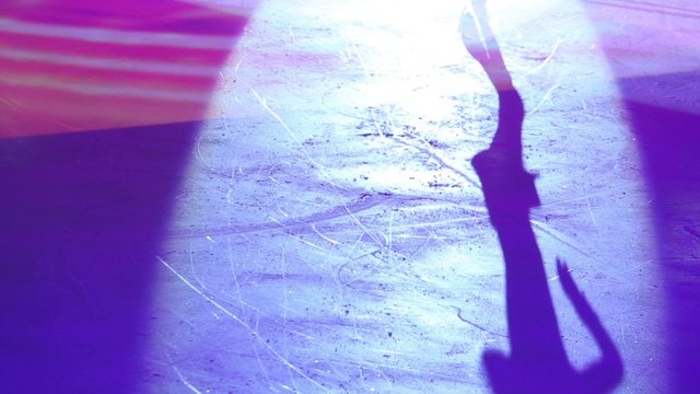 Colored shadow of girl figure skating at competition on stadium