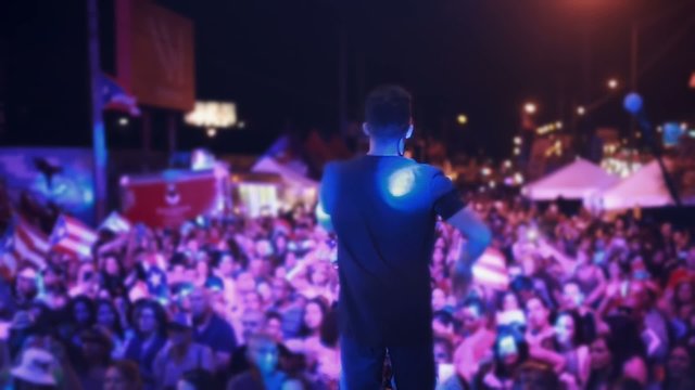Man singing on stage in front of crowd of people