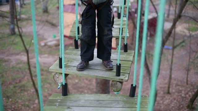 Legs of children climber standing on hanging wood of rope course