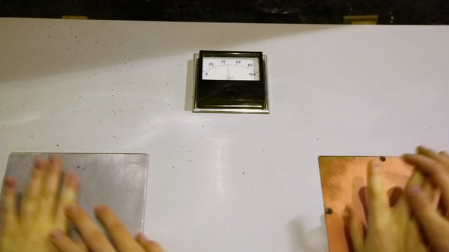 Two kids put hands at electrode plates. 