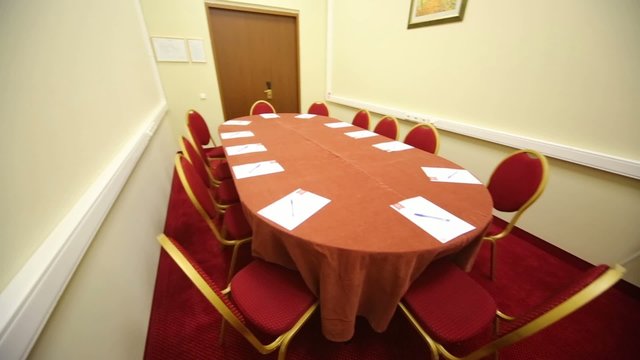 Empty conference room with oval table and red carpet on floor