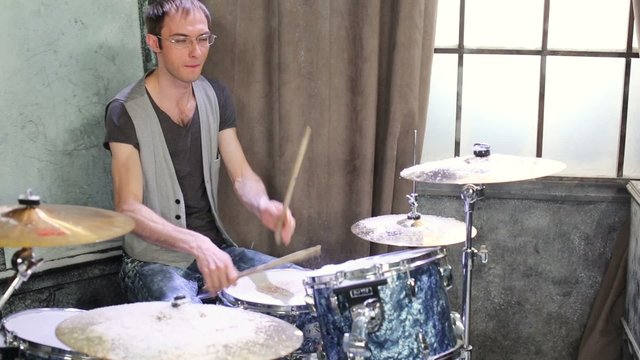 Drummer plays drums in room powdered snow with curtain