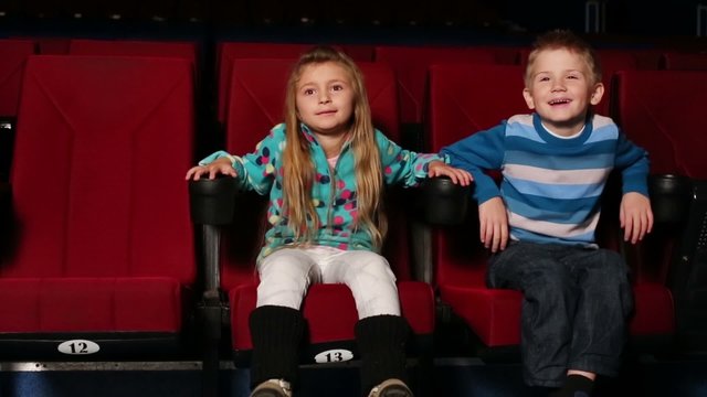 Little boy and girl with an interest watching a comedy at cinema