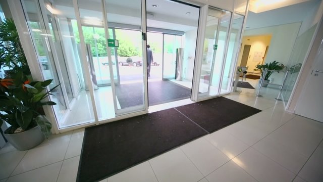 Man walks through entrance glass door of office building 