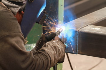 welder is welding steel pipe with all safety equipment