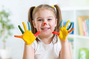 Fototapeta premium Five year old girl with hands painted in colorful paints