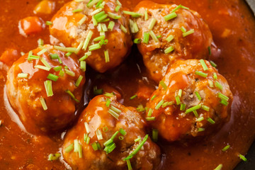 Meatballs with tomato sauce on black pan