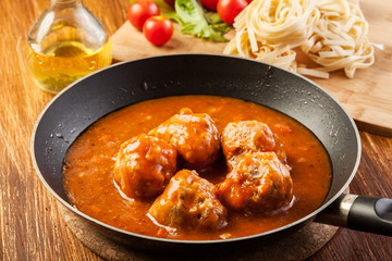 Meatballs with tomato sauce on black pan