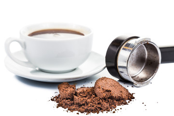 Spent coffee grounds with portafilter and espresso at background