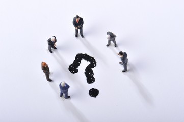 クエスチョンマークを囲んで会議をしているビジネスマン