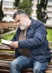 Attractive bearded man reading in a park
