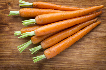Fresh carrots on the wooden background.