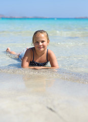 Cute little smiling girl plays at tropical beach