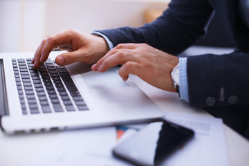 Fototapeta premium Businessman sitting at table with laptop and documents