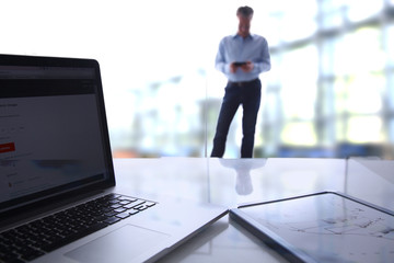 Laptop  computer on  desk , businessman standing in the