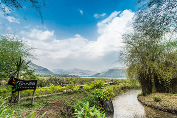 Bammboo bridge near reservoir with mountain and sky view
