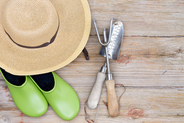 Hat, Gardening Shoes and Tools on Wood Background