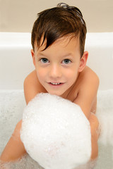 Cute boy taking a bath with foam