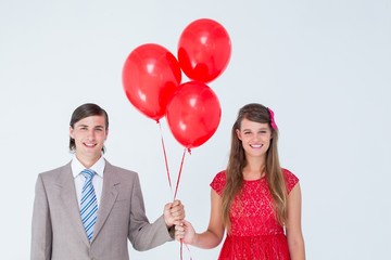 Smiling geeky couple holding red balloons