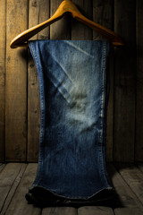 Blue jean with wood hanger on wood background, low key image