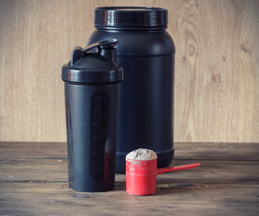 Whey protein powder in scoop  and plastic shaker