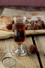 Small glass of brandy and homemade candies on wooden table