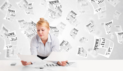 Business woman at desk with stock market newspapers