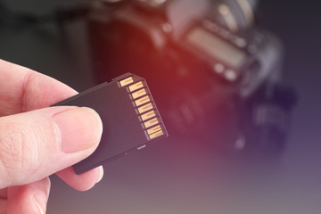 Hand holds SD Card against DSLR camera