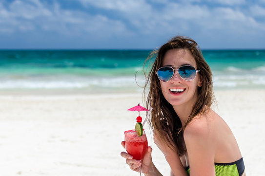 Young cute woman with fresh cocktail at tropical sandy beach